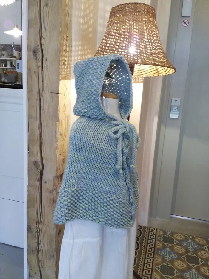 Hand-knitted baby and toddler poncho with hood, cable detail, and textured stitches – shown in chunky wool, from the Wry Cable Poncho PDF knitting pattern.