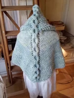 Hand-knitted baby and toddler poncho with hood, cable detail, and textured stitches – shown in chunky wool, from the Wry Cable Poncho PDF knitting pattern.