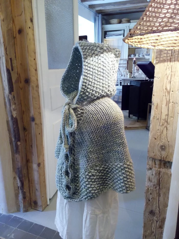 Hand-knitted baby and toddler poncho with hood, cable detail, and textured stitches – shown in chunky wool, from the Wry Cable Poncho PDF knitting pattern.
