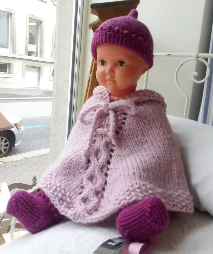 Hand-knitted baby and toddler poncho with hood, cable detail, and textured stitches – shown in chunky wool, from the Wry Cable Poncho PDF knitting pattern.